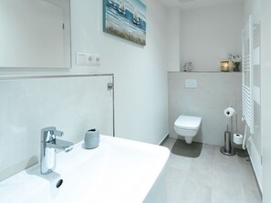 Casa de banho moderna com lavatório branco, sanita e zona de duche.