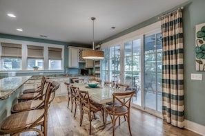 A spacious kitchen with a large island, wooden chairs, and a dining table.