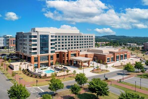 A modern hotel with multiple floors, a swimming pool, and a landscaped courtyard. - UNC Charlotte Marriott Hotel & Conference Center (Charlotte)