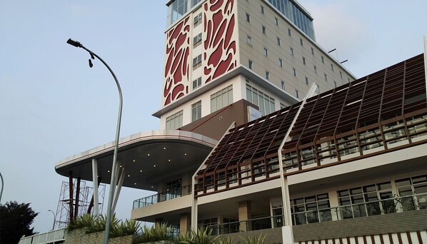 A modern building with a curved roof structure, large windows, and a prominent red and white facade. - Kartika One Hotel Jakarta (Jakarta)