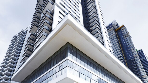 Un edificio moderno de gran altura con una fachada blanca destacada y amplias ventanas.