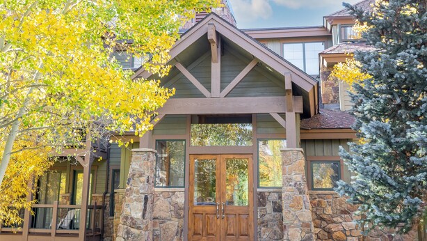 A two-story house with a stone facade, a wooden front door, and a covered porch.