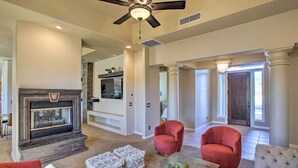 A spacious living room with a fireplace, red armchairs, and a glass coffee table. - Mtn View! Group-Friendly Getaway in Fountain Hills (Fountain Hills)