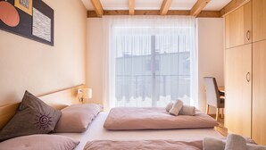 A bedroom with a bed, pillows, a desk, and a wardrobe. - Kronsun Glück Apartment 100 m² at Kronplatz Valley Station with 3 Separate Bedrooms (Percha)