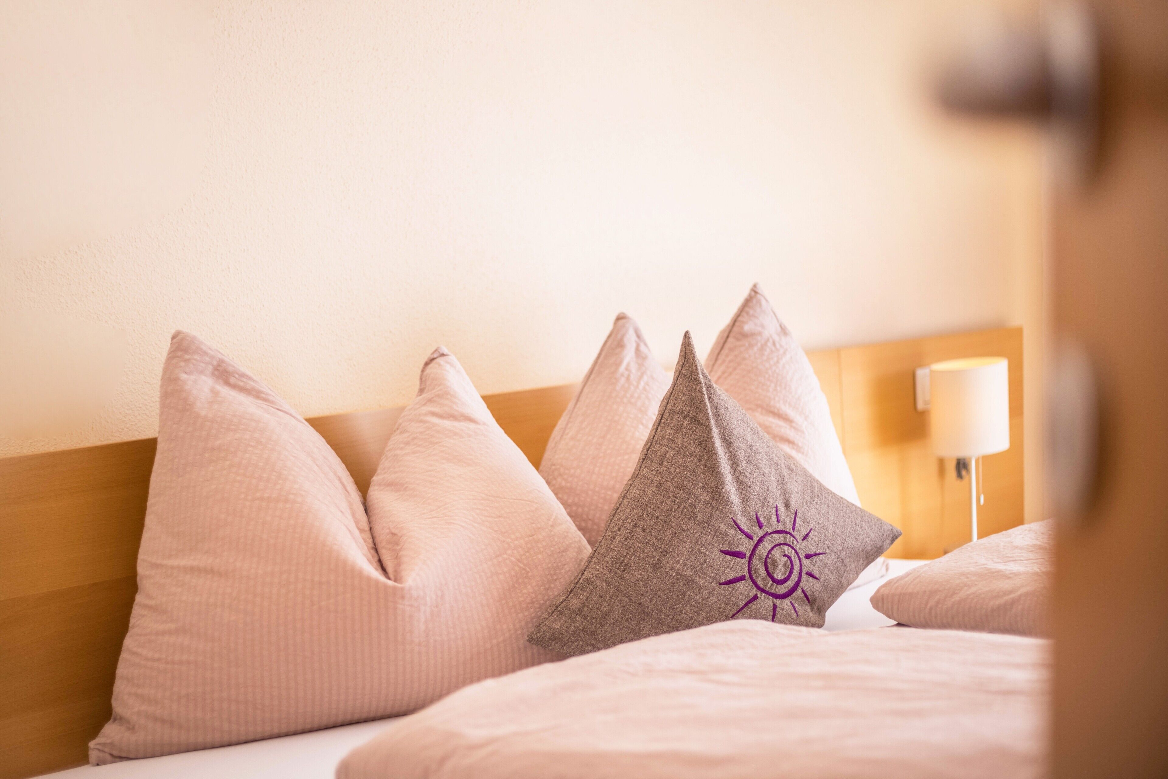 A bed with multiple pillows and a bedside lamp.