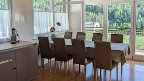 A dining area with a wooden ceiling, large windows, and a view of a forest. - Kronsun Glück Apartment 100 m² at Kronplatz Valley Station with 3 Separate Bedrooms (Percha)