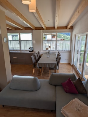 Un intérieur moderne comprenant une table à manger, un canapé et de grandes fenêtres donnant sur l’extérieur.