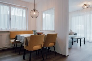 A dining area with a table, chairs, and a hanging light fixture.