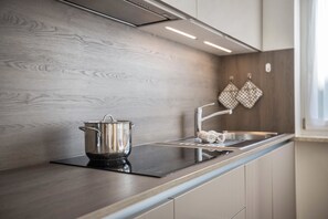 A modern kitchen with a wooden backsplash, stainless steel appliances, and a window providing natural light.