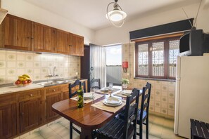 A kitchen with wooden cabinets, a dining table set for four, and a refrigerator.