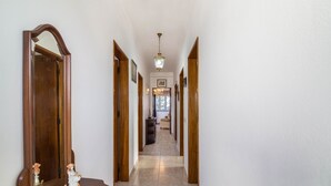 A hallway with wooden doors, a chandelier, and a statue on a table.