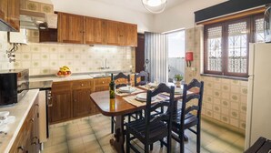 A kitchen with wooden cabinets, a dining table set for four, and a window with decorative iron bars.