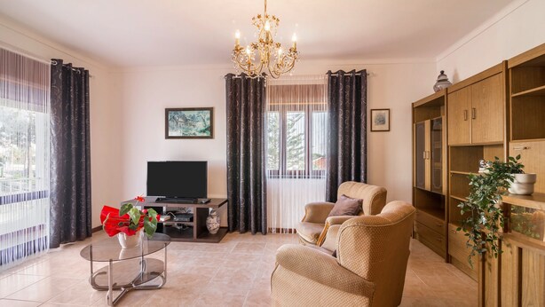 A living room with a sofa, TV, and a chandelier.