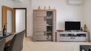 A living room with a TV, entertainment unit, and a dining area with chairs and a table. - Luminous Apartment Oura Nascente close to the Sea with Balcony & Wi-Fi (Albufeira)
