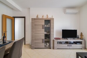 Un salon équipé d’un téléviseur, d’un meuble de rangement pour les appareils multimédias et d’un coin repas avec des chaises et une table.
