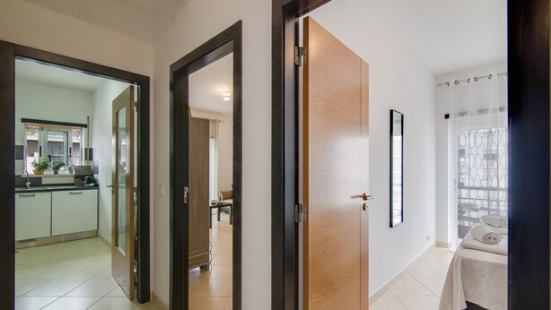 A hotel room with a bed, a bathroom, and a kitchen area visible through an open door. - Luminous Apartment Oura Nascente close to the Sea with Balcony & Wi-Fi (Albufeira)
