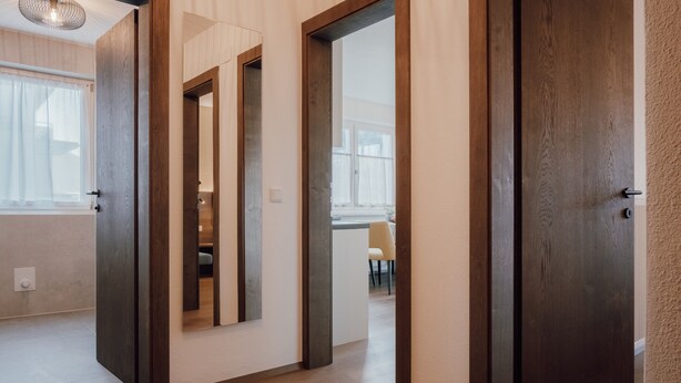 A hallway with wooden flooring, a door, and a window with curtains. - Apartment 'Kronsun Harmonie' right at the Kronplatz valley station (Percha)