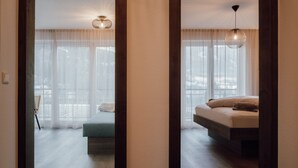 A bedroom with a bed, a chair, and a view through sheer curtains. - Apartment 'Kronsun Harmonie' right at the Kronplatz valley station (Percha)