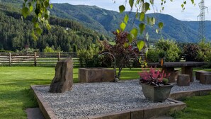 A landscaped garden with a stone bench, a large planter with flowers, and a tree stump. - Apartment 'Kronsun Harmonie' right at the Kronplatz valley station (Percha)