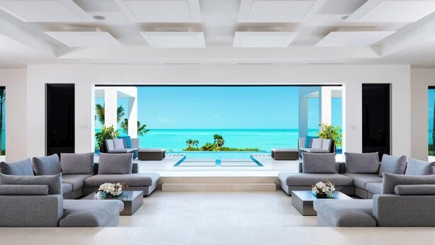 A modern living room with a large window overlooking a beach and ocean.