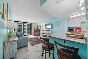 Enjoy a contemporary kitchen and living area with a stove, granite countertop, and comfortable seating.