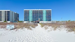 Ein Strandhotel mit einem Schild, auf dem 'Island Winds East' steht, und einem Strandweg, der zum Eingang führt.