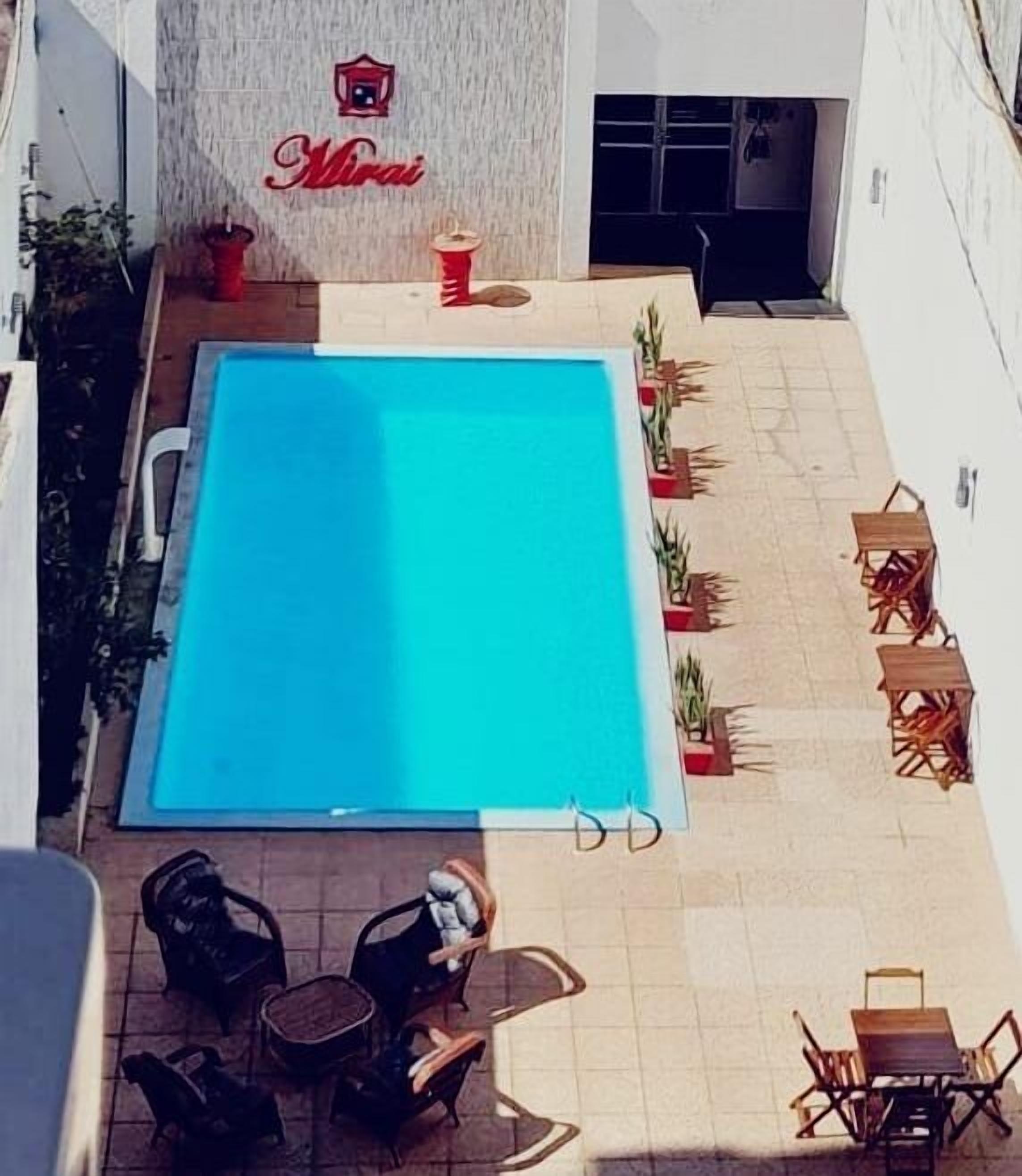 A rooftop pool with a clear blue pool, surrounded by outdoor seating and potted plants.