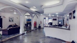 Un vestíbulo amplio con una recepción, zona de estar y vistas al exterior.