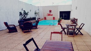 Un patio con piscina, mobiliario exterior y una pared con el nombre 'Mirai'.