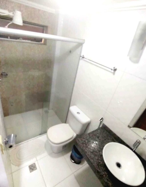 Un baño pequeño con inodoro, lavamanos y zona de ducha.