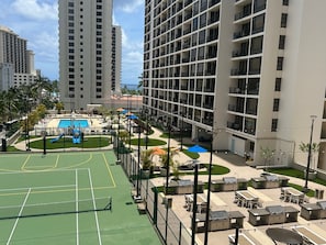 A multi-story hotel with a rooftop pool, tennis court, and outdoor seating areas. - Waikiki Banyan 3410 Stunning Ocean, Surfer & Sunset View's (Honolulu)
