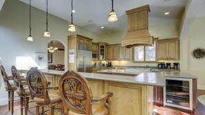 A spacious kitchen with wooden cabinets, a large island, and a dining area with ornate chairs.