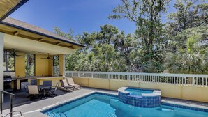 A pool area with a hot tub, lounge chairs, and a dining table.