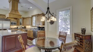 A spacious kitchen with a central island, stainless steel appliances, and a chandelier.
