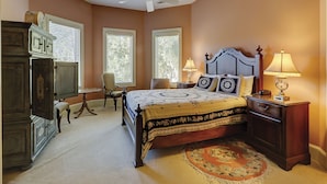 A bedroom with a bed, two bedside tables, a chair, a desk, and a ceiling fan.