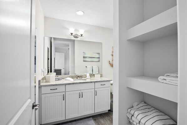 A modern bathroom with a white vanity, a large mirror, and a towel rack.