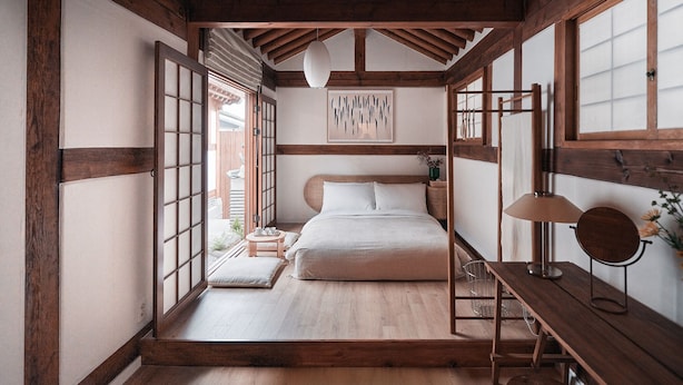 Une chambre de style japonais traditionnel, avec un sol recouvert de tatamis, un lit bas en bois, une porte coulissante de type shoji et une lanterne en papier suspendue au plafond.