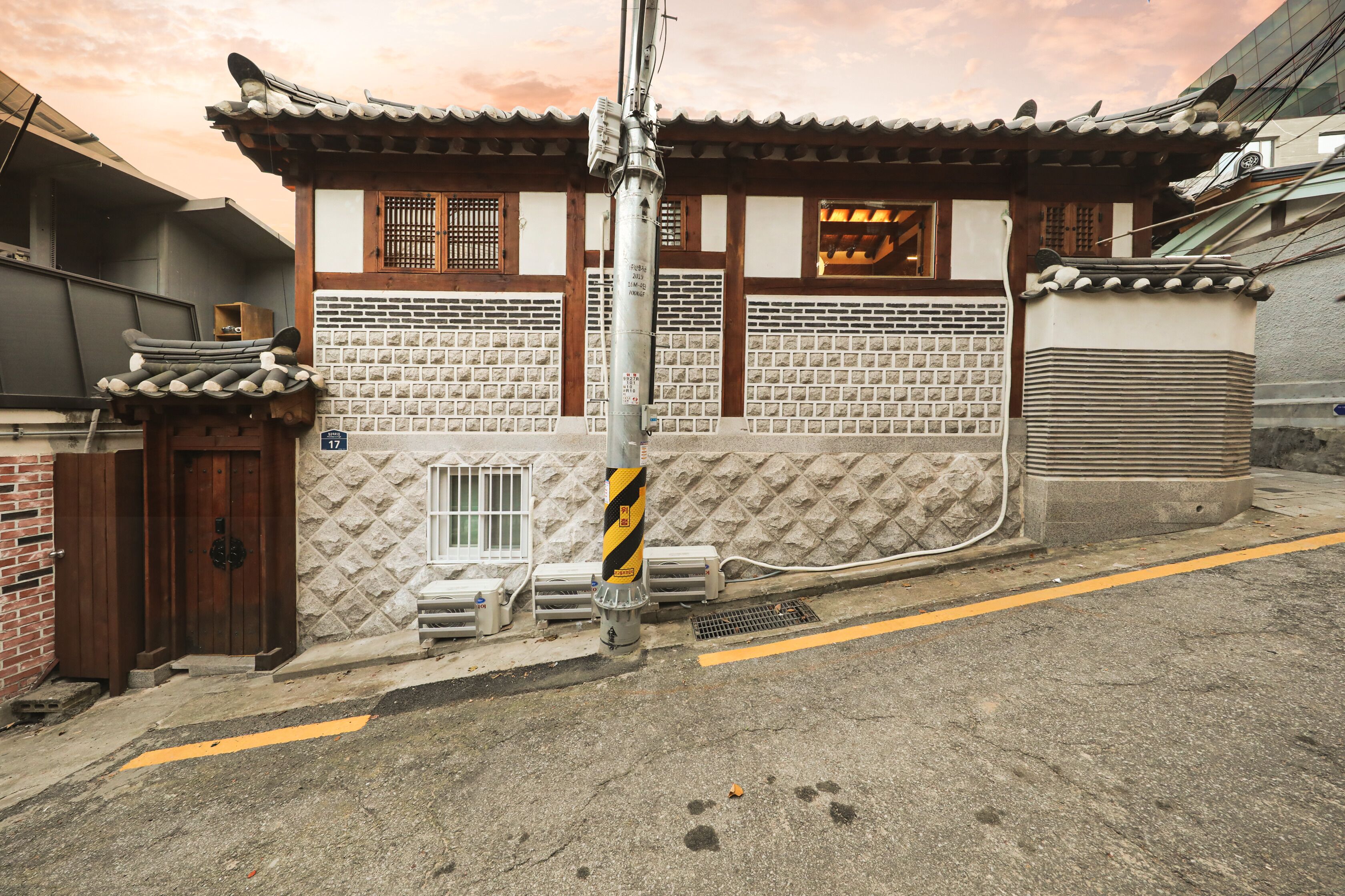 A traditional Korean building with a tiled roof, wooden doors, and a brick wall.