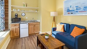 A compact living space with a kitchenette, a blue sofa, a wooden coffee table, and a floor lamp. - Downtown Friday Harbor! Adults Only (CCS#2) (Friday Harbor)