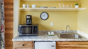 A kitchen with a microwave, coffee maker, sink, and shelves with cups and glasses. - Downtown Friday Harbor! Adults Only (CCS#2) (Friday Harbor)
