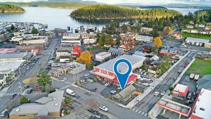 An aerial view of a town with a marina, commercial buildings, and a prominent red building with a gas station.
