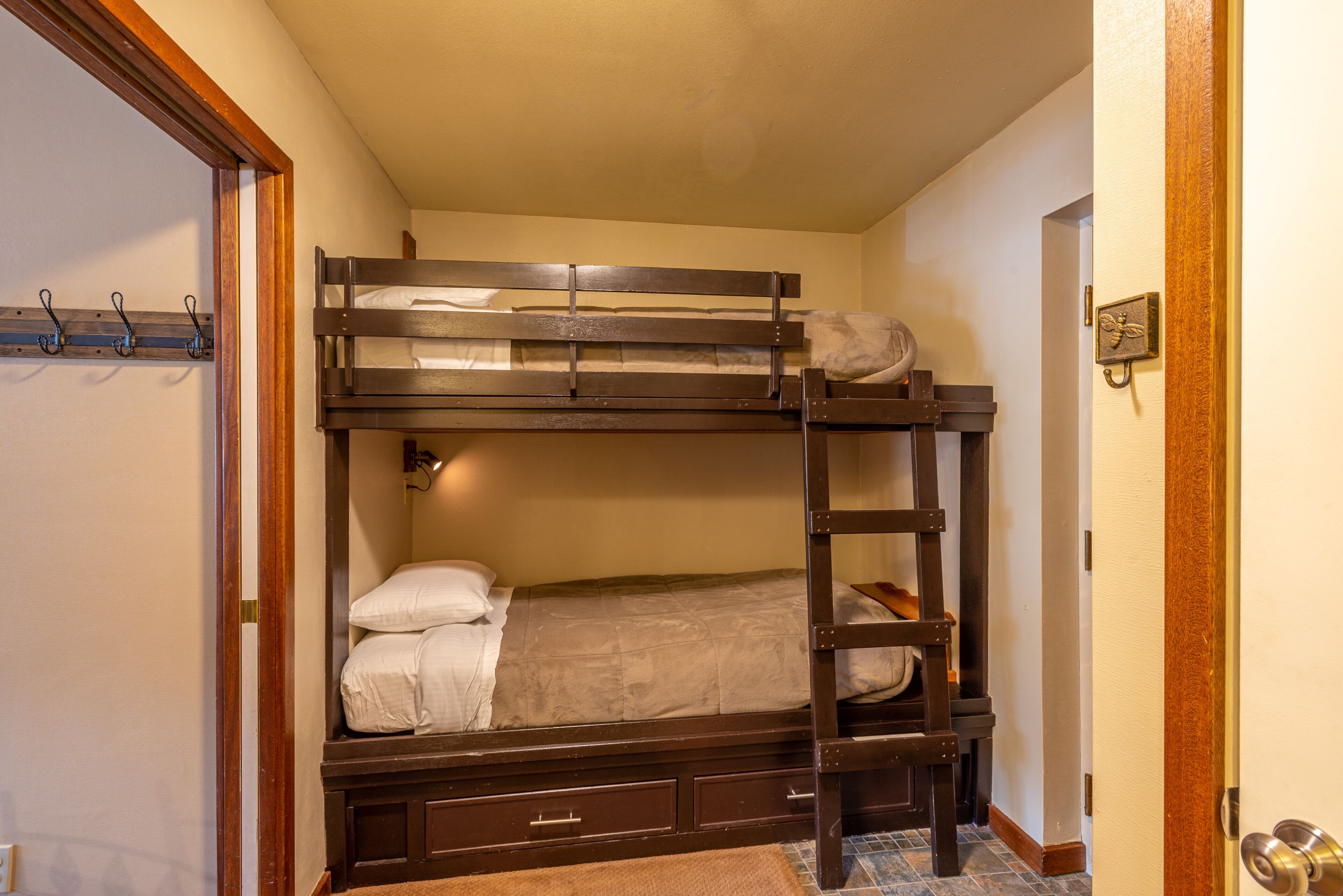 A bunk bed with a ladder, a small shelf, and a wall-mounted hook.