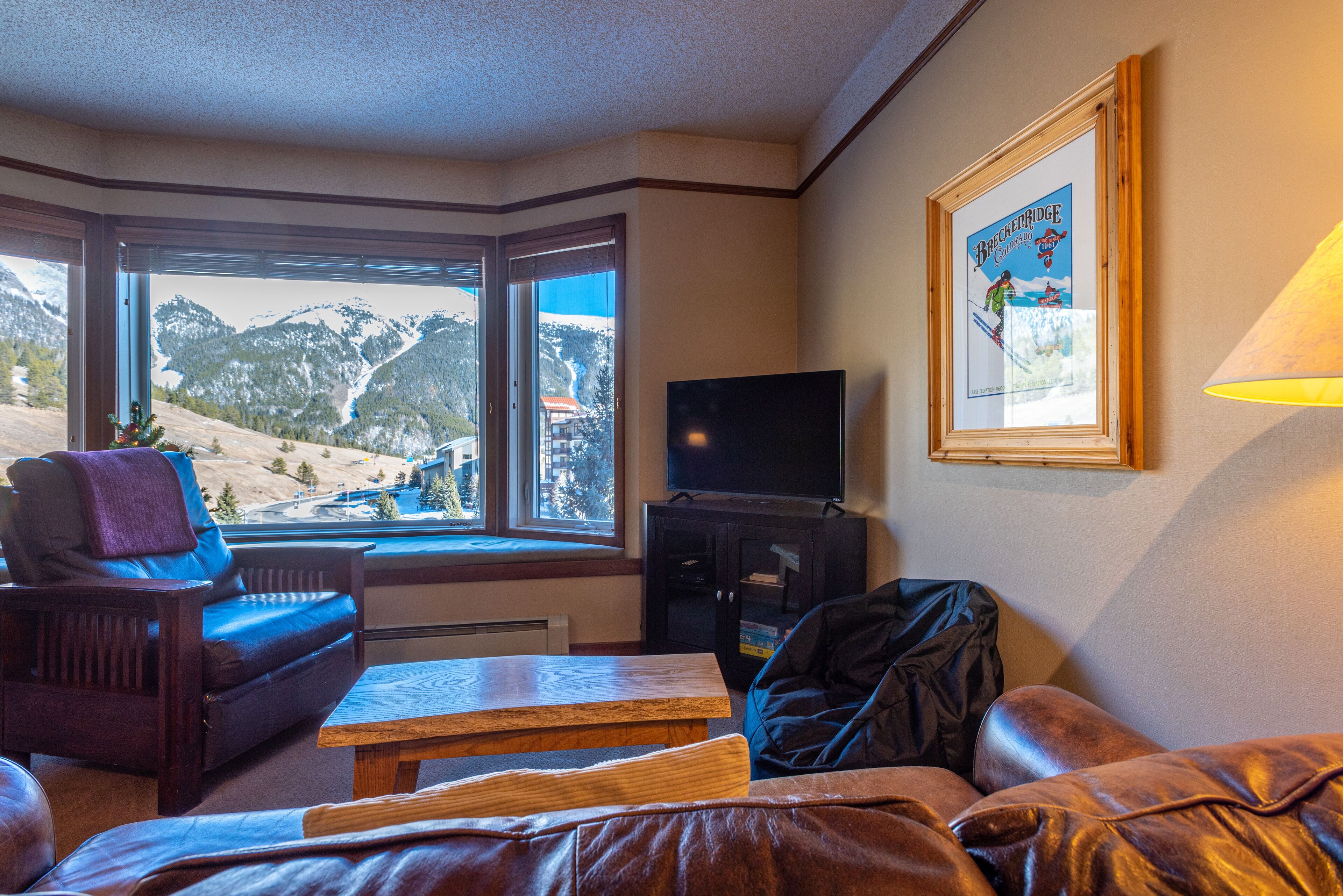 A living room with a view of mountains, a television, and a framed picture on the wall.