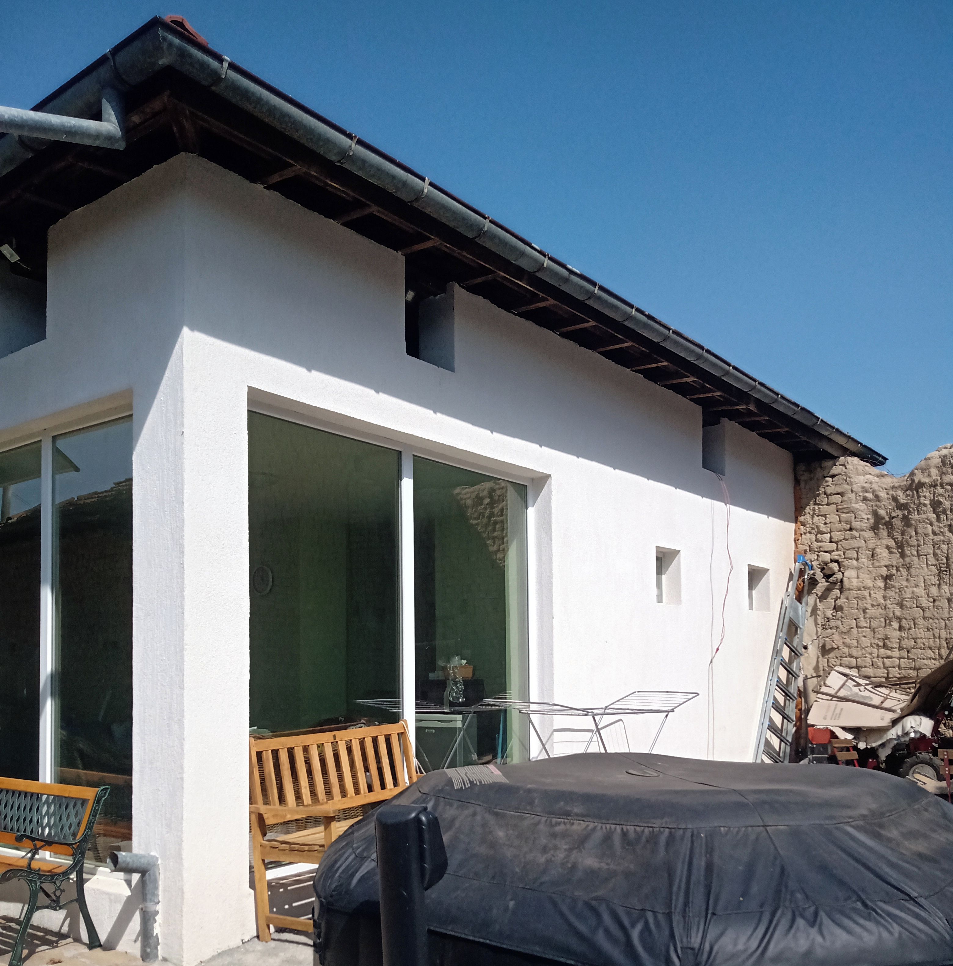 Una casa moderna con un espacio de estar cubierto al aire libre, una piscina inflable grande y un garaje visible.