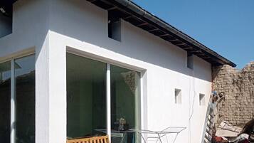 Una casa moderna con un espacio de estar cubierto al aire libre, una piscina inflable grande y un garaje visible.