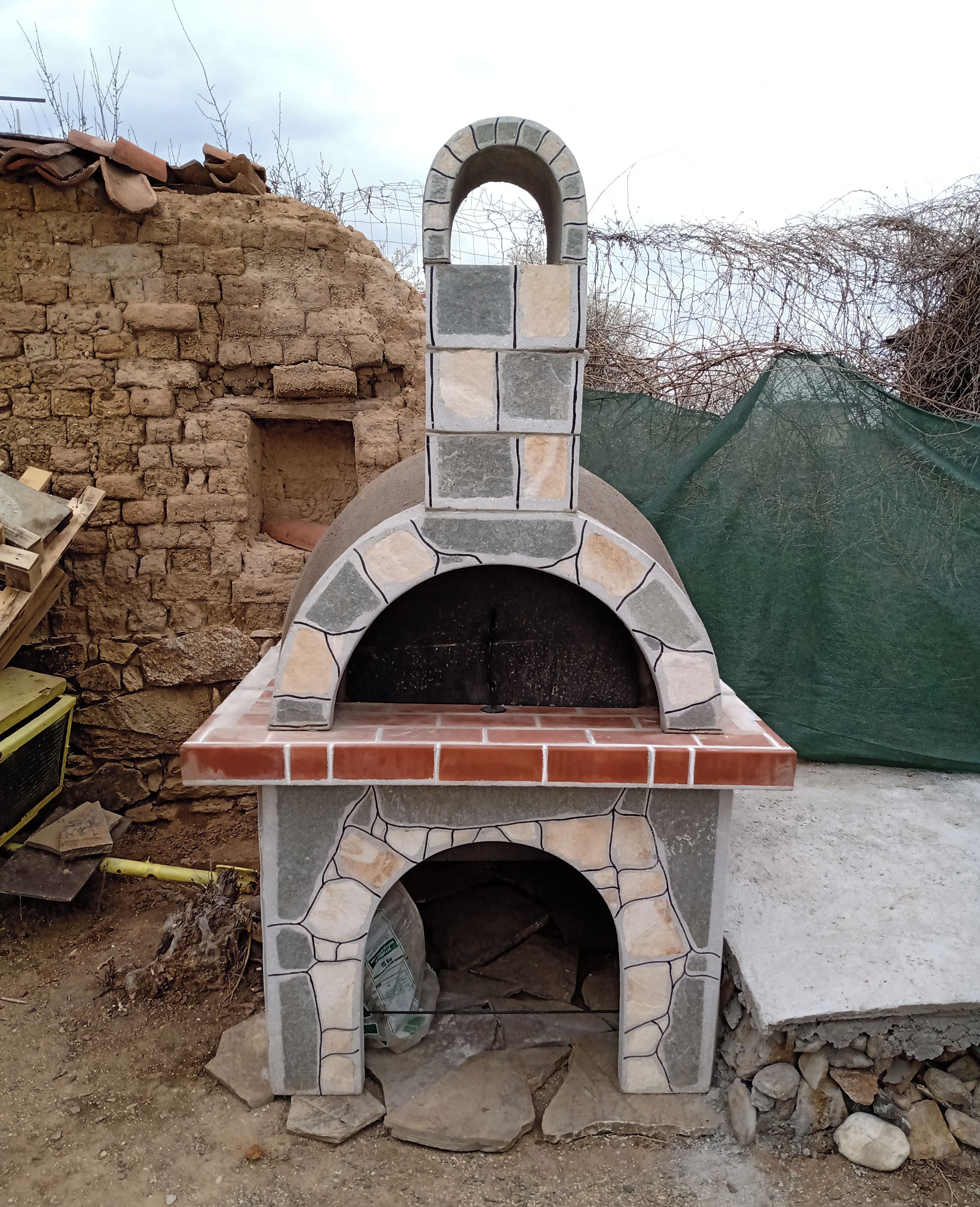 Un four à pizza extérieur en pierre, avec une base en briques et une arche en pierre sur le dessus.