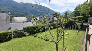 Un quartiere residenziale con case, un giardino e un sentiero che conduce verso una montagna.