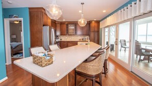 A modern kitchen with a large island, wooden cabinets, and a view to the outside. - Seneca Memories: Luxury Lakeside Home on Seneca Lake! (Penn Yan)