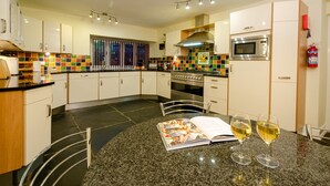 A modern kitchen with white cabinets, a granite countertop, a built-in oven, and a microwave. - Swallows House - Four Bedroom House, Sleeps 8 (Skelwith)