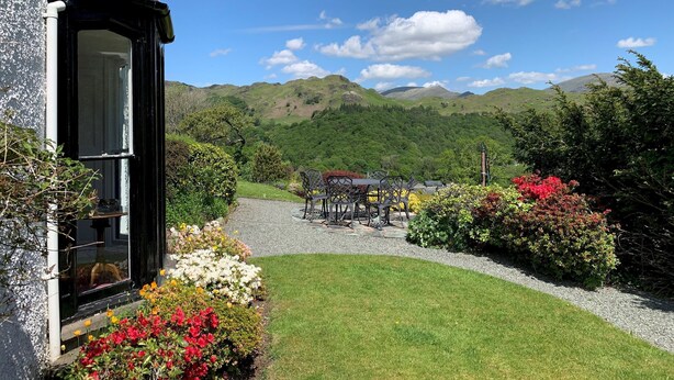 A house with a garden, a gravel path, and a view of green hills in the distance. - Swallows House - Four Bedroom House, Sleeps 8 (Skelwith)